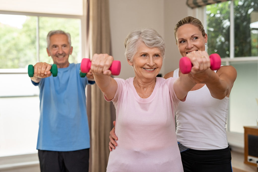 Smiling resident lifting a dumbbell during a fitness class.