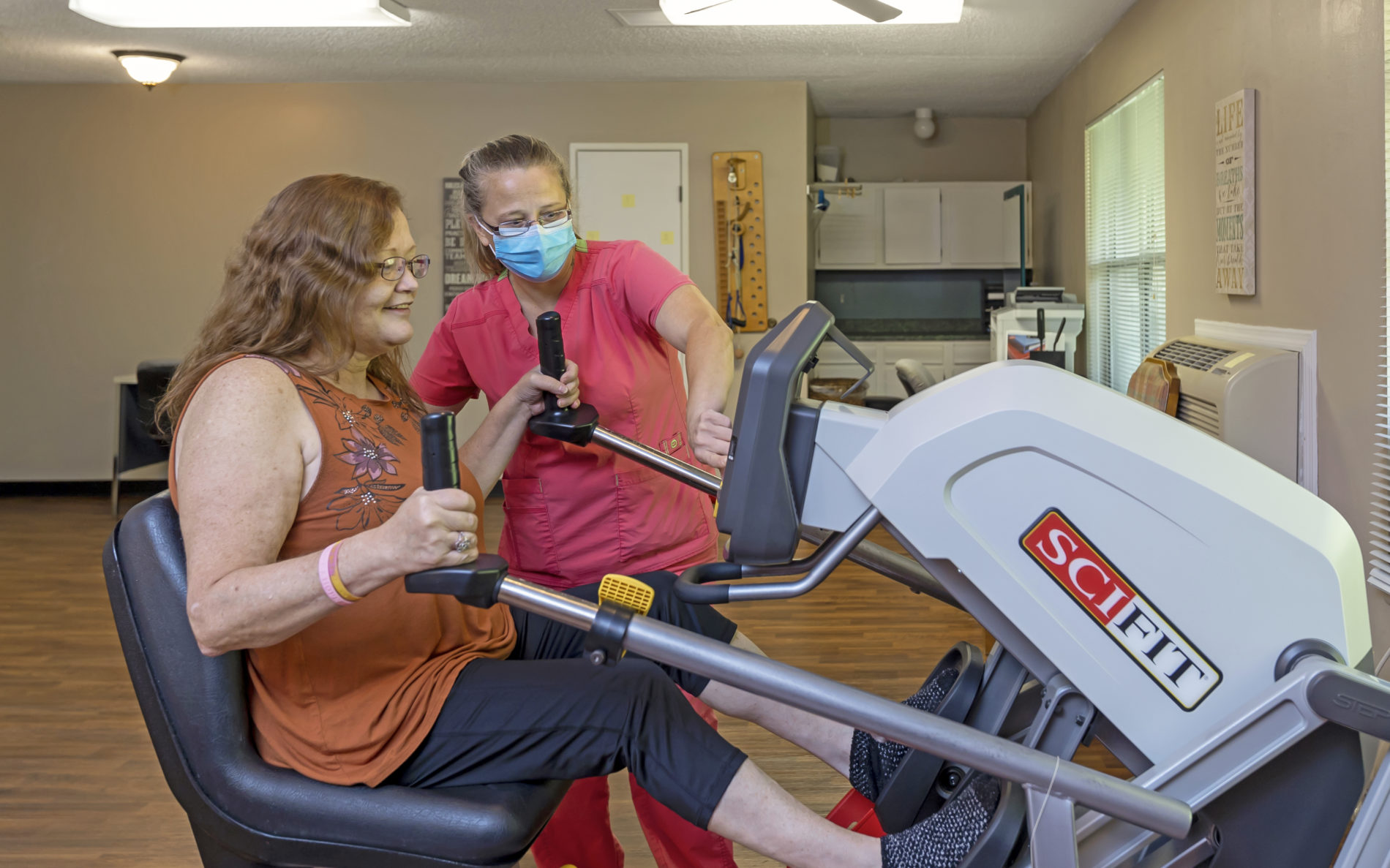 Female staff member helping woman on exercise machine